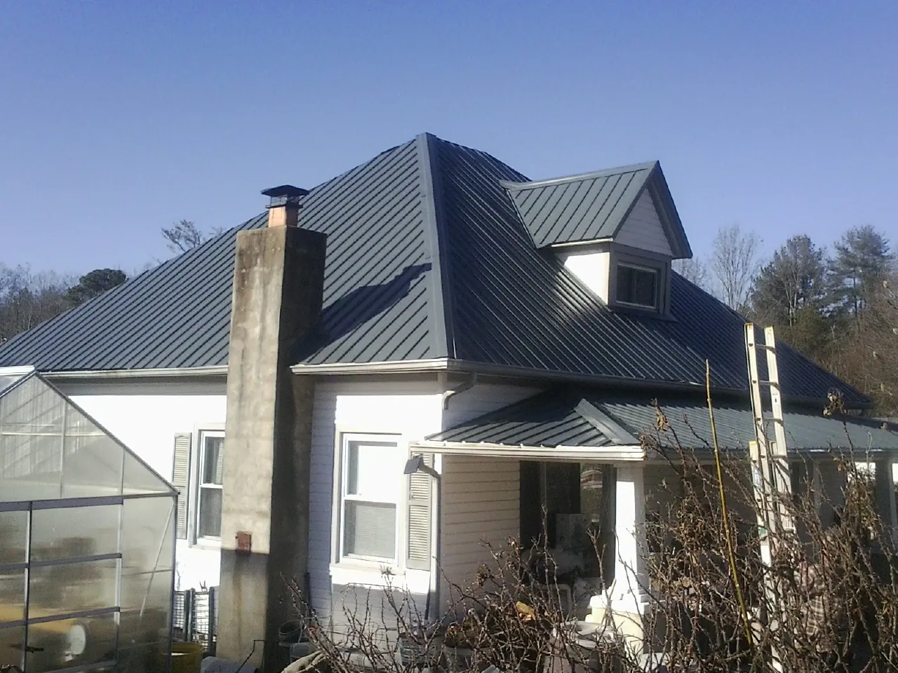 Dark blue standing seam metal roof on a white farmhouse with dormer — Slate & Tile Roof Repair by Roofing Brothers in Noxen