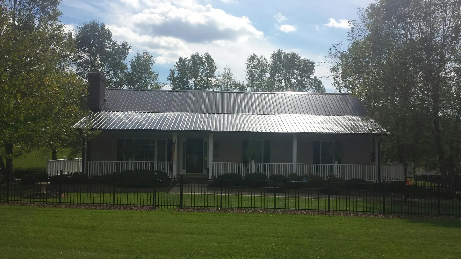 Gray metal roof on a brick ranch with a full width front porch — Gutter Guard Installation work by our crew in Noxen