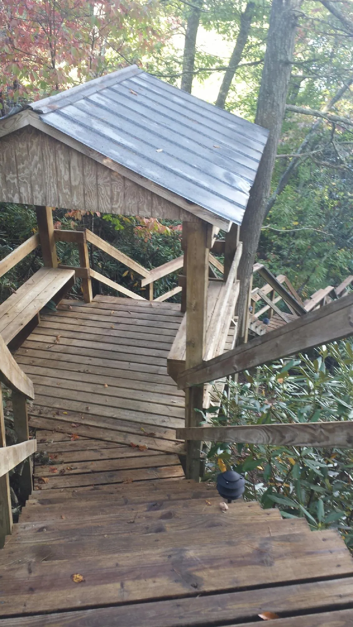 Metal roofed shelter over wooden steps on a wooded walkway — Skylight Repair & Installation work by our crew in Noxen