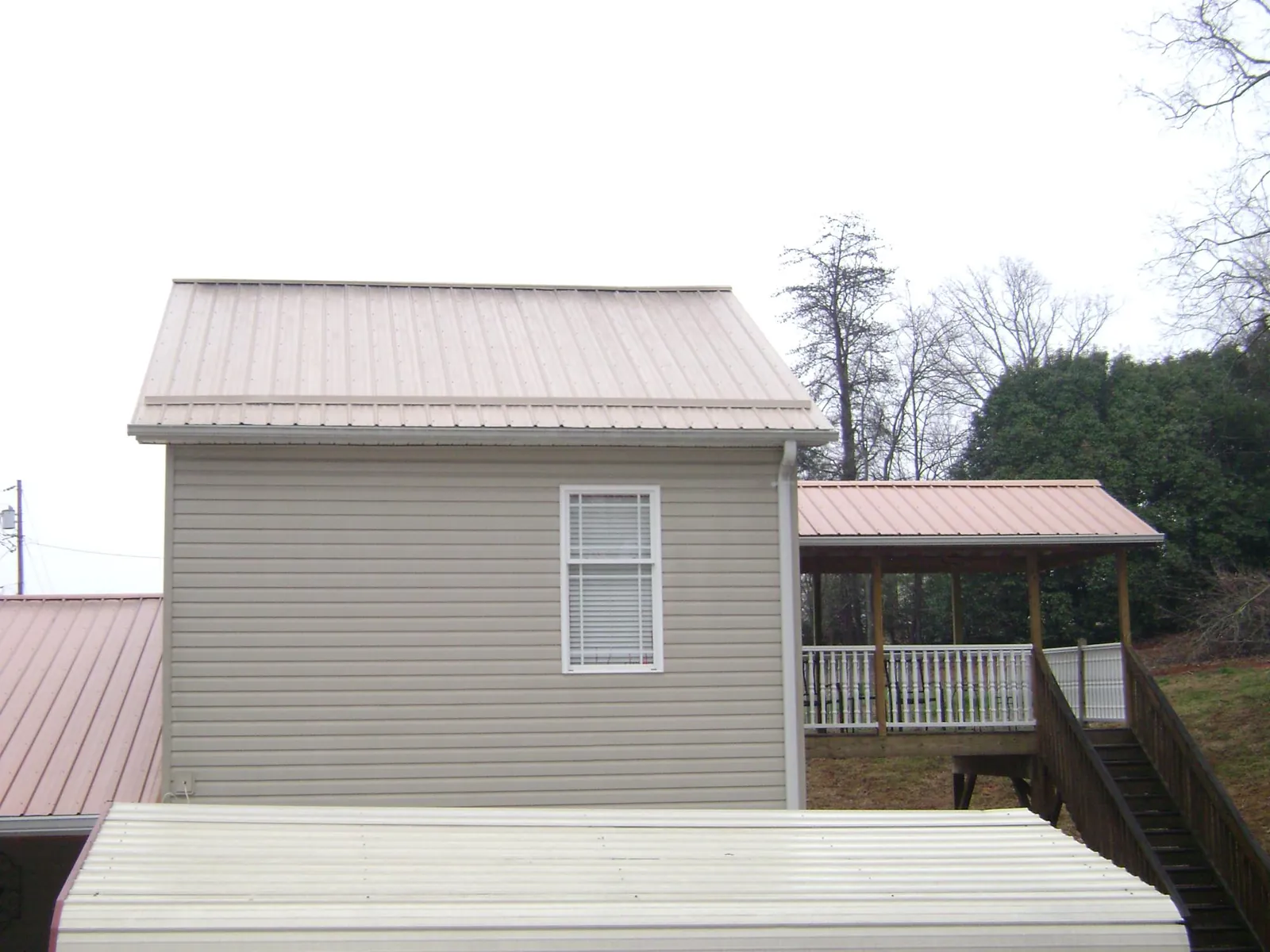 Tan metal roofs on a two story addition and attached porch, from a Roof Replacement job in Noxen