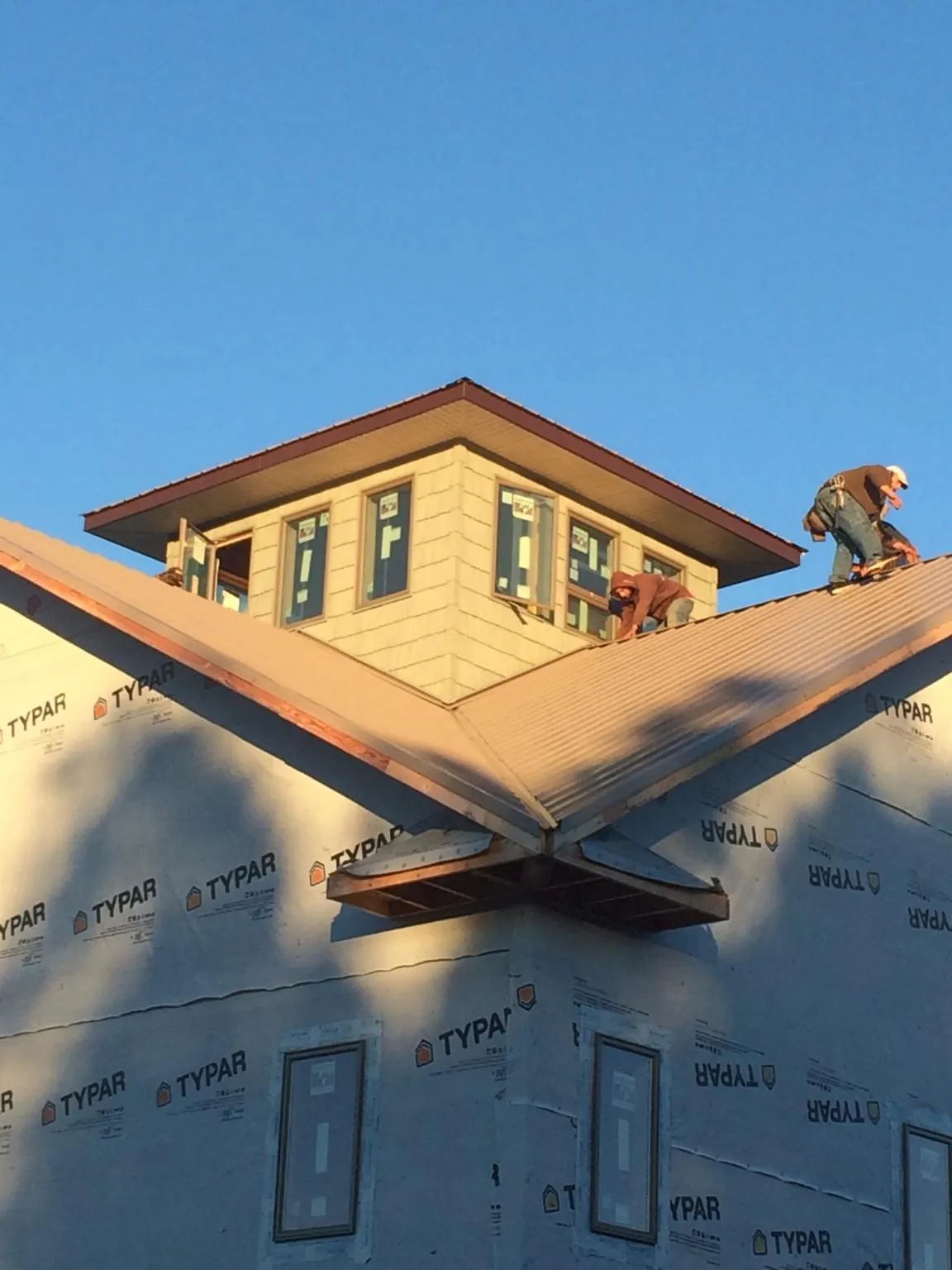 Roofers working around a rooftop cupola on a new metal roof at sunset — Roof Waterproofing in Noxen by Roofing Brothers